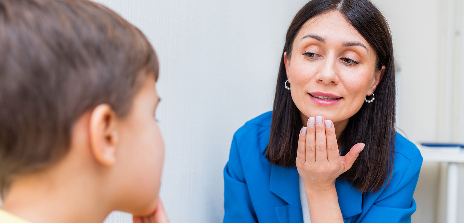 Sprachtherapeutin hilft einem Jungen, seine Sprachfehler zu korrigieren